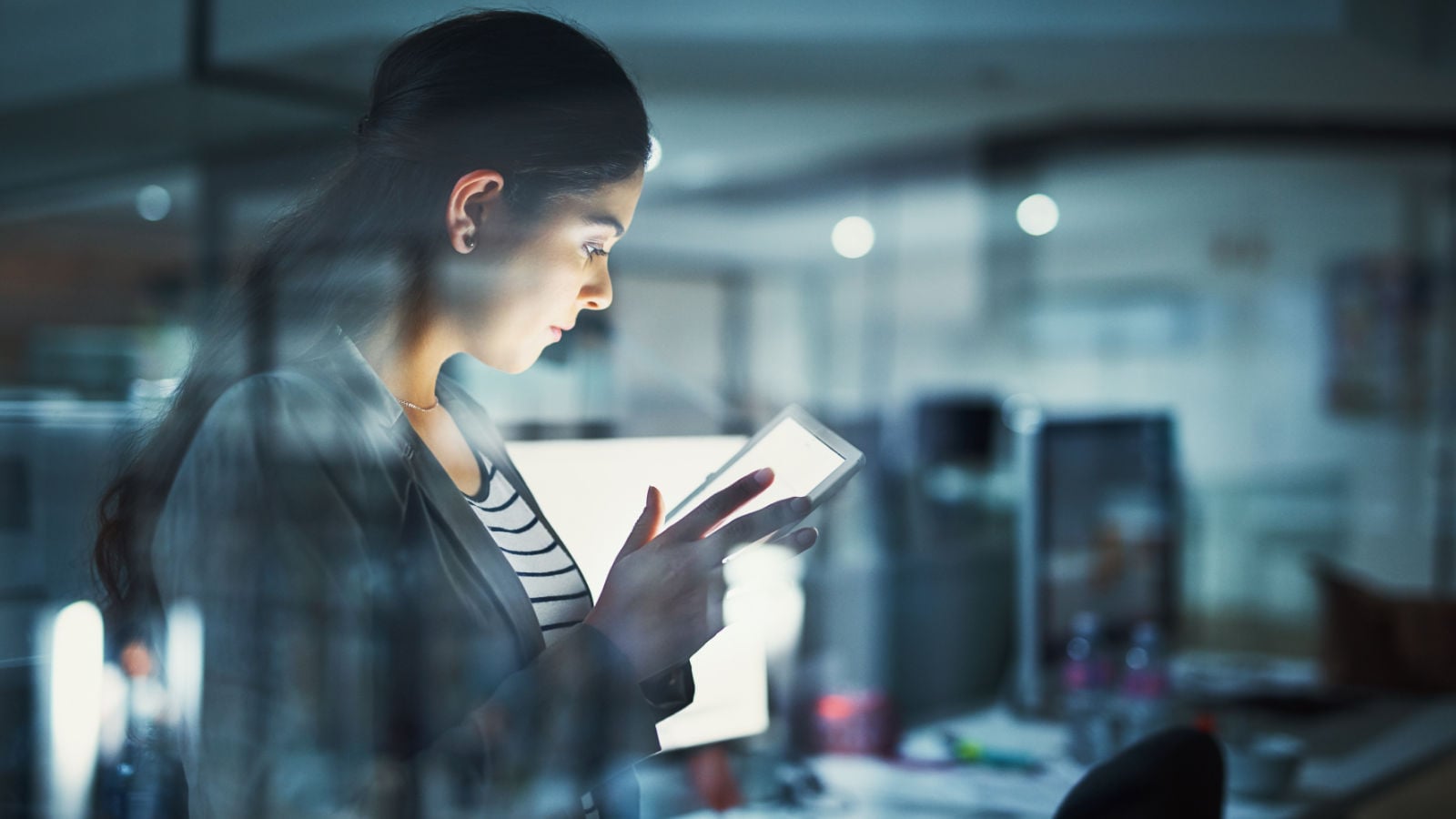 Young businesswoman working late in the office on digital tablet