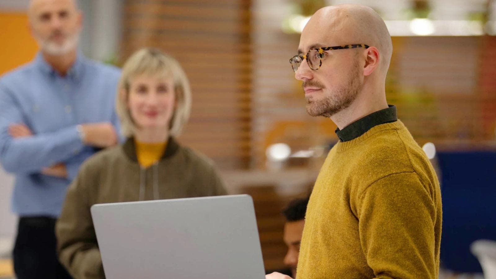 man with a laptop with colleagues in the background